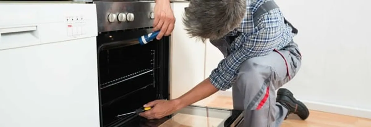 Oven repair technician inspecting and servicing an electric oven in Memphis, TN