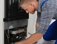 Refrigerator repair technician servicing the compressor and condenser area in Memphis, TN