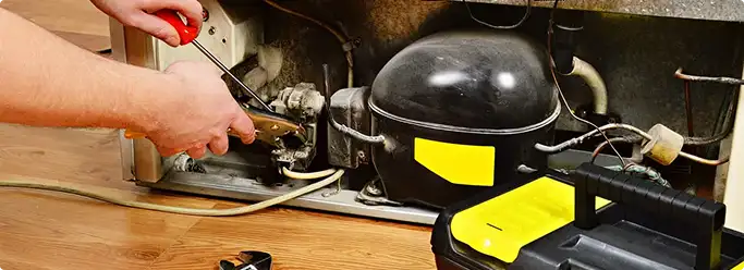 Refrigerator repair technician fixing the compressor and wiring in Memphis, TN